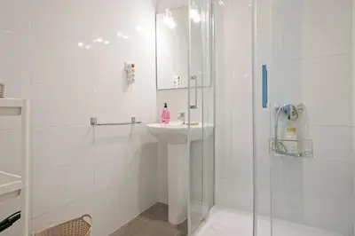 a white bathroom with a sink and a shower at Dialez Holidays - Colomeres in Gavà