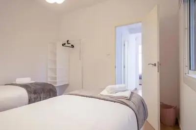 a white bedroom with two beds and a window at Dialez Holidays - Colomeres in Gavà