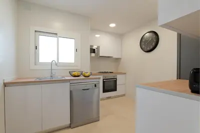 a kitchen with white cabinets and a clock on the wall at Rosari II - Vivienda Privada con Parking in Vilassar de Mar