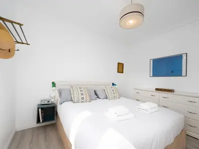 a white bedroom with a white bed and a tv at Cosy Sants Apartment in Barcelona