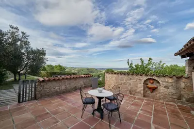 a patio with a table and chairs and a stone wall at LuxRural Montserrat | Piscina con Vistas Únicas in Marganell