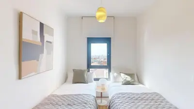 two beds in a white room with a window at Impressive apartment for 6 in Gracia in Barcelona