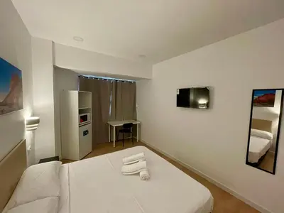 a bedroom with a white bed with towels on it at Lux Hostal in Hospitalet de Llobregat