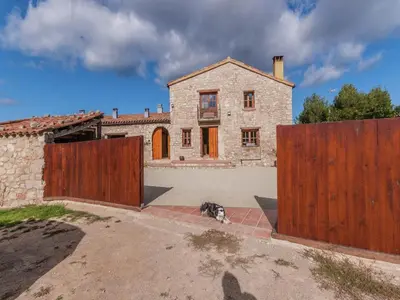 a dog sitting in front of a house with two gates at Farmhouse near Barcelona with Pool in Marganell