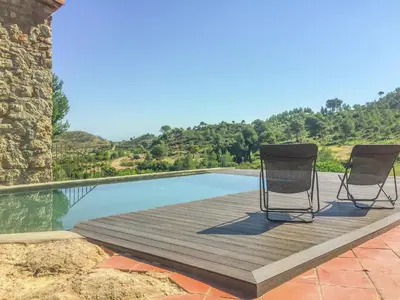 two chairs sitting on a wooden deck next to a pool at Farmhouse near Barcelona with Pool in Marganell