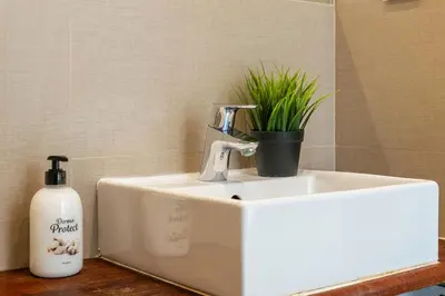a white sink with a bottle of soap and a plant at Marblau Beach Vacation and Downtown Sitges in Sitges