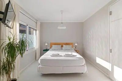 a white bedroom with a large white bed in it at Marblau Beach Vacation and Downtown Sitges in Sitges