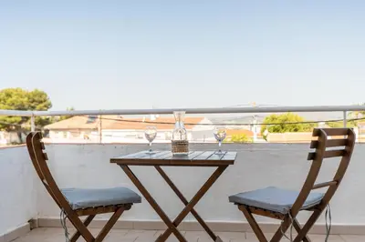 a table with two chairs and wine glasses on a balcony at Can Montardo in Sant Pere de Ribes