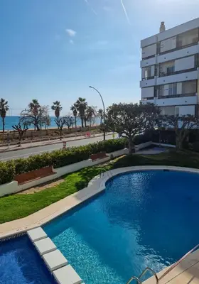 a swimming pool in front of a building at Voramar, Apartamento a primera línea de mar y con piscina in Canet de Mar