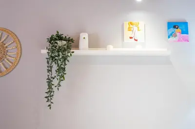 a white shelf with a plant on a wall at Apartamento Completo junto playa y Centro Bcn in Badalona
