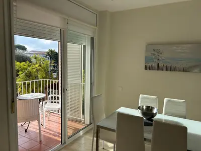 a dining room with a table and a view of a balcony at Apartamentos ELMA1 in Castelldefels