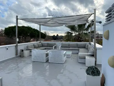 a patio with a couch and chairs on a roof at Apartamentos ELMA1 in Castelldefels