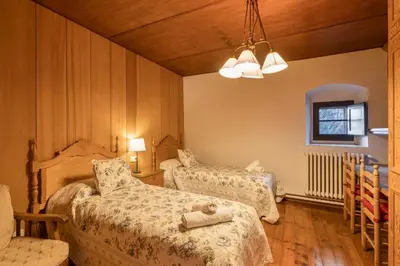 a bedroom with two beds and a chair and a window at Masia Brugarolas in Castelltersol