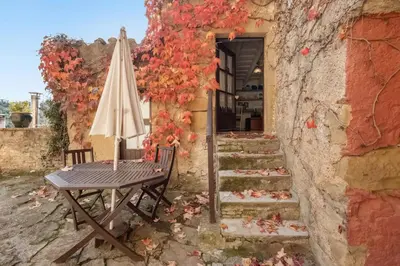 a table and an umbrella next to a stone building at Masia Brugarolas in Castelltersol