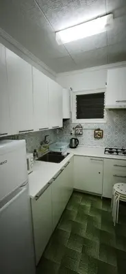 a kitchen with white cabinets and a green floor at Playa de Sant Adrià de Besòs in Sant Adria de Besos