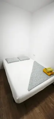a white bed sitting on top of a wooden floor at Playa de Sant Adrià de Besòs in Sant Adria de Besos