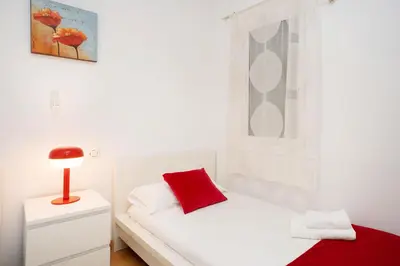 a white bedroom with a red pillow on a bed at Apartamento Comte Borrell in Barcelona
