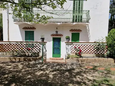 a white house with green doors and a balcony at Cal Llanto in Torrellas de Foix