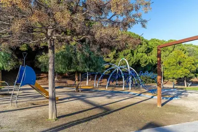 a park with a playground with a blue slide at Canela Homes COSTA LA PINEDA in Castelldefels