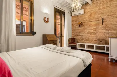 a bedroom with a large white bed with a brick wall at Gràcia Loft Terrace BBQ AC & Fiber Wi-Fi in Barcelona