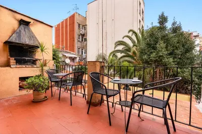 a patio with chairs and tables on a balcony at Gràcia Loft Terrace BBQ AC & Fiber Wi-Fi in Barcelona