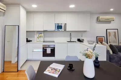a kitchen with white cabinets and a table with a vase at Cozy Apartment III - Les Corts in Barcelona