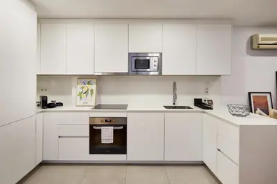 a white kitchen with white cabinets and a microwave at Cozy Apartment III - Les Corts in Barcelona