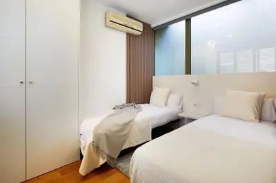two beds in a room with white walls at Cozy Apartment III - Les Corts in Barcelona