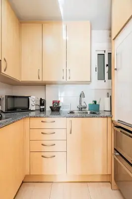 a kitchen with wooden cabinets and a sink at Sitges Seafront RIBERA in Sitges