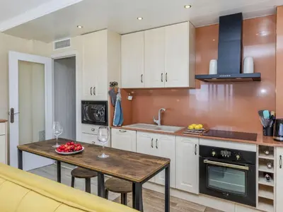 a kitchen with white cabinets and a table with fruit on it at Apartment Xaloc by Interhome in Cubelles