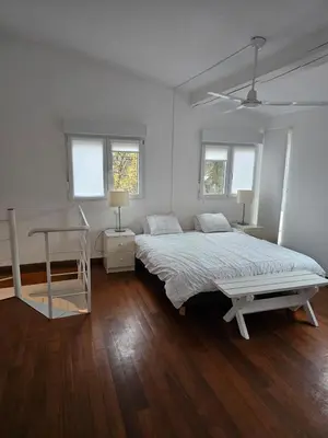 a white bedroom with a bed and two windows at La Casa Delviga in Can Trabal