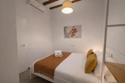 a white bedroom with a bed with two towels on it at Boutique Murillo in Barcelona