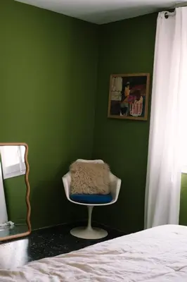 a green room with a chair in a bedroom at Masia Can Pares in Sant Pere de Ribes