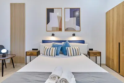 a bedroom with a large white bed with blue pillows at Sant Adrià Urban Suites by gaiarooms in Badalona