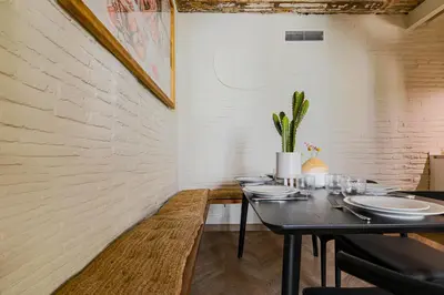 a dining room with a table with plates and a plant at En Ville Boutique Apartments Boqueria Market in Barcelona
