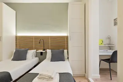 two beds in a room with a desk and a chair at Enjoy Apartments VP Camp Nou 1 in Barcelona