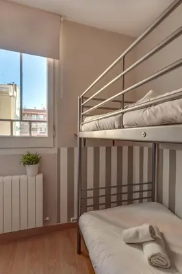 a bedroom with two bunk beds and a window at 2-bedroom Bright and Classic Sagrada Familia Apartment in Barcelona