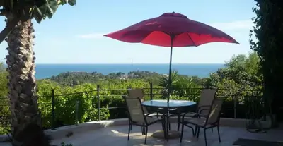 a table with chairs and a red umbrella on a balcony at Las Buganvillas in Castelldefels