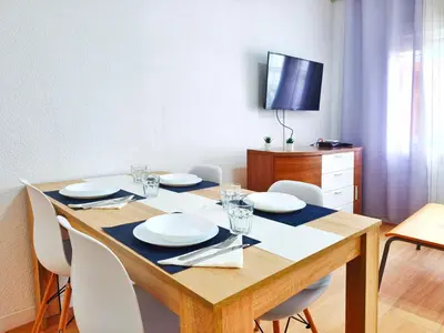a dining room table with white chairs and a television at Apartamento en Vilassar de Mar, Costa de Barcelona in Vilassar de Mar