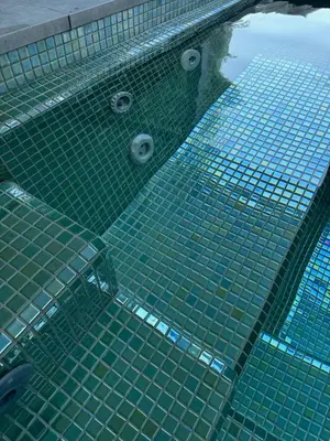 a swimming pool with green tiles in the water at Suite with Pool Barcelona in Vilassar de Dalt