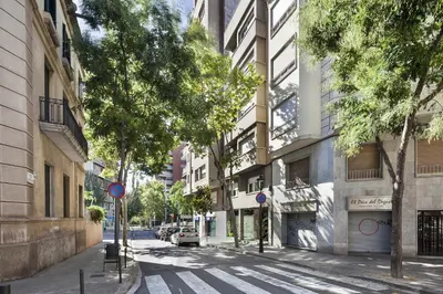 an empty city street with trees and buildings at Sarria Attic in Barcelona