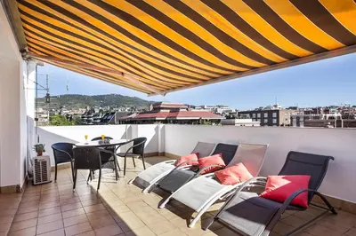 a balcony with chairs and a table on a roof at Sarria Attic in Barcelona