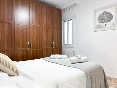 a bedroom with two beds and wooden cabinets at Apartment Iolanda in Vilanova i la Geltrú