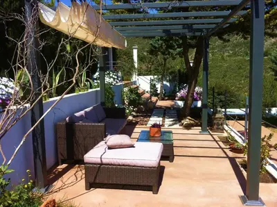 a patio with wicker chairs and a pergola at Suite in private villa view on sea in Castelldefels