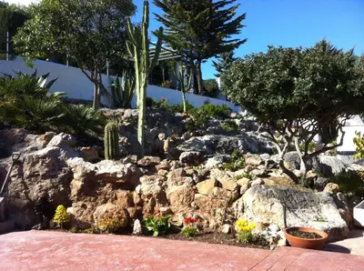 a garden with rocks and trees and plants at Suite in private villa view on sea in Castelldefels