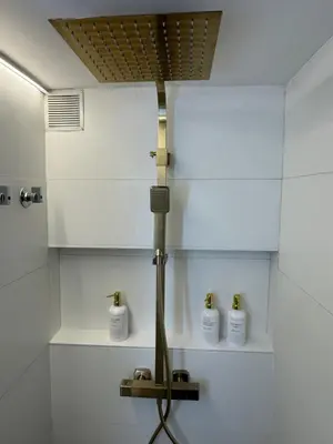 a bathroom with a shower with three bottles on a shelf at SuitePoolBarcelona in Vilassar de Dalt