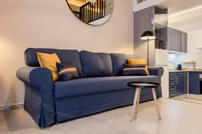 a blue couch in a living room with a stool at Novus Homes Barcelona Plaza España in Barcelona