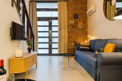 a living room with a blue couch and a tv at Novus Homes Barcelona Plaza España in Barcelona