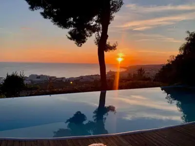 a pool with a tree and the sunset in the background at Casa Roca Lujo mediterráneo con piscina infinity in Sitges