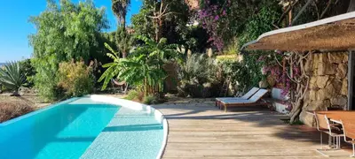 a swimming pool sitting next to a wooden deck at Casa Roca Lujo mediterráneo con piscina infinity in Sitges